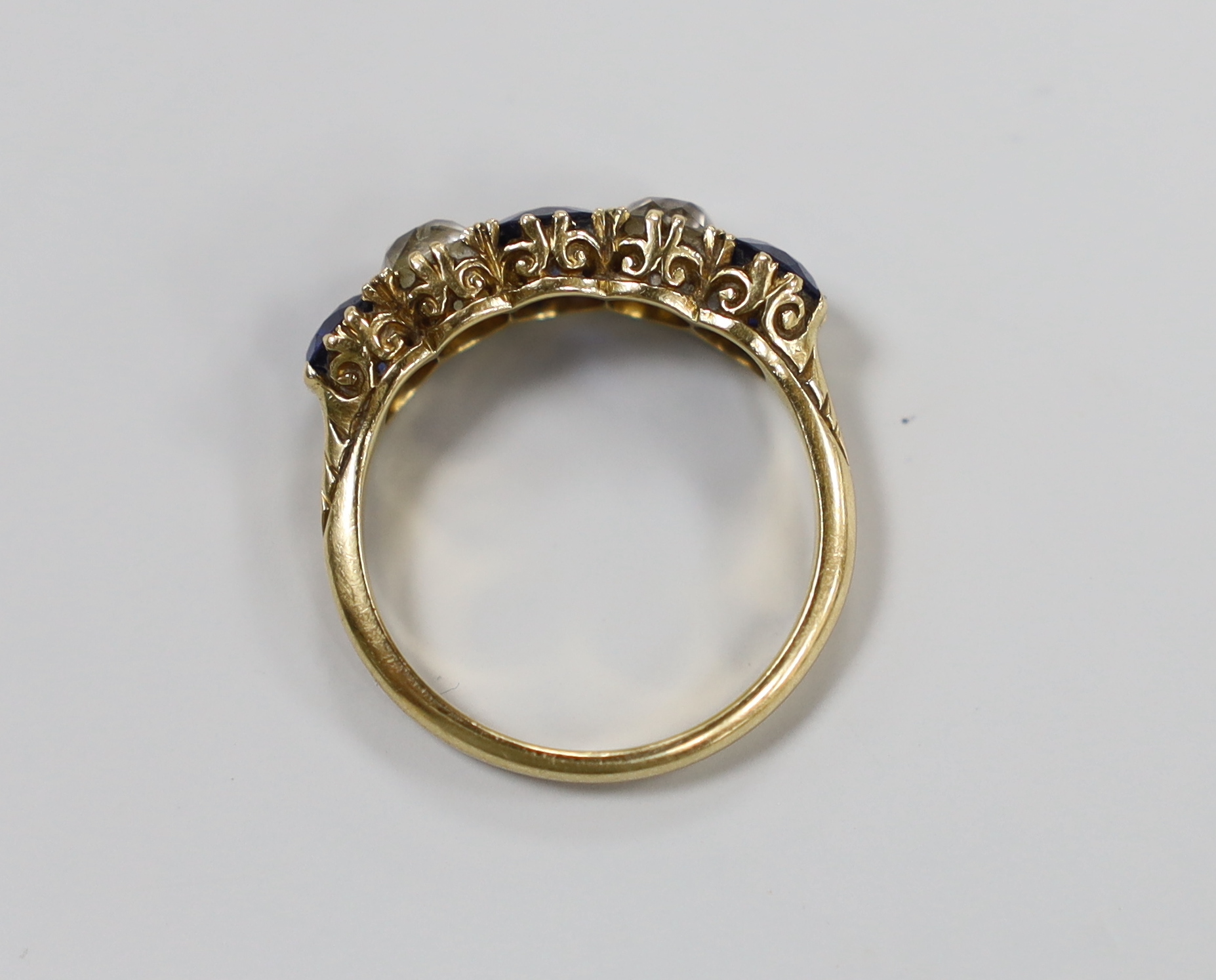 An 18ct gold, three stone blue paste and two stone diamond set half hoop ring